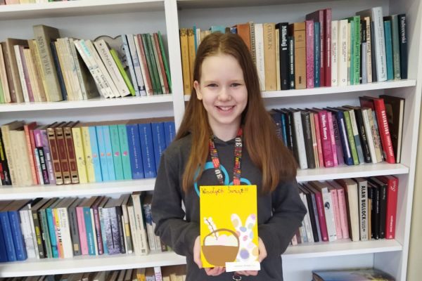 Uśmiechnięta uczennica prezentuje przygotowaną przez siebie pracę