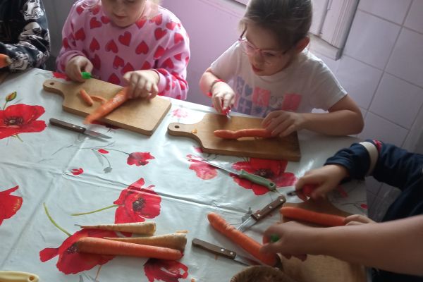 Warsztaty kulinarne- dzieci obierają i kroją warzywa do zupy.