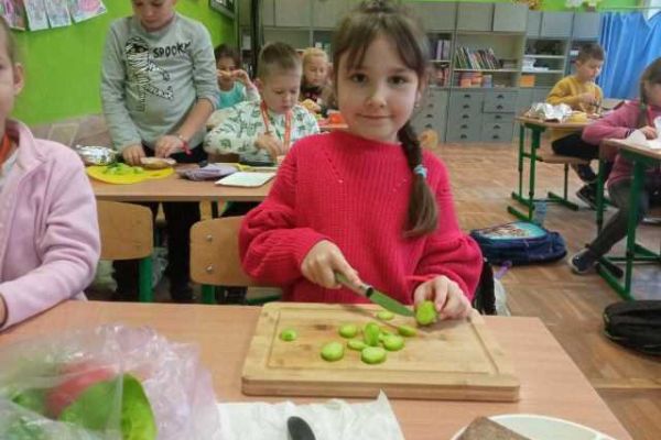 Dzieci z klasy 1b kroją warzywa.