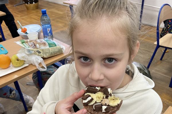 Uczennica smakuje zdrową kanapkę.