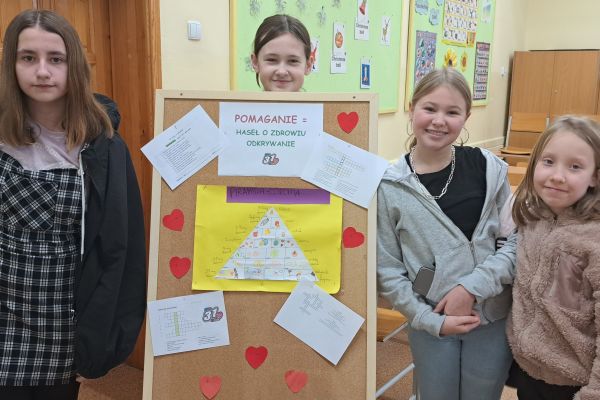 uczniowie przy tablicy z hasłem POMAGANIE = HASEŁ O ZDROWIU ODKRYWANIE