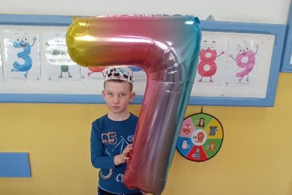 Chłopiec trzyma w ręce balon z okazji 7 urodzin